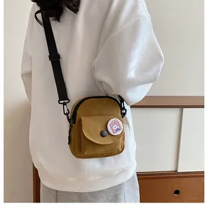 Détail du petit sac bandoulière en toile jaune gingembre avec badge lapin et sangle réglable