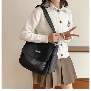 Detailed side view of a black canvas messenger bag featuring a stylish logo patch