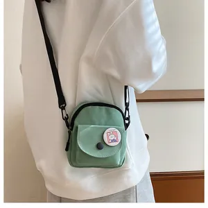 Détail du petit sac bandoulière en toile vert clair avec badge lapin mignon et sangle