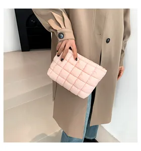 Nahaufnahme der rosa gesteppten Kosmetiktasche mit goldenem Reißverschluss in der Hand