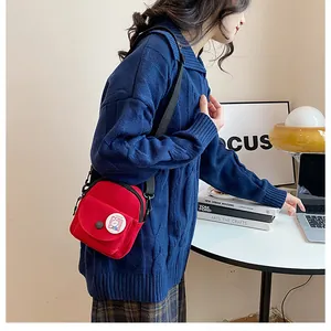 Vue détaillée du mini sac bandoulière rouge en toile avec badge lapin et lanière