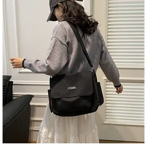Side view of large black nylon messenger bag with adjustable strap and side pockets