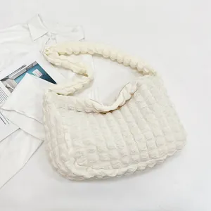 Macro shot of white pleated cloud bag texture and ruffled fabric detail on shoulder strap
