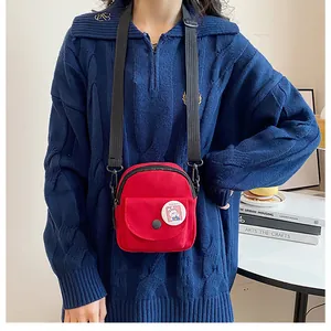 Gros plan sur un petit sac bandoulière en toile rouge avec badge lapin sur un pull bleu