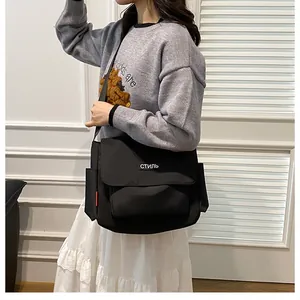 Detailed view of black canvas messenger bag with white СТИЛЬ text and red side tag