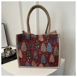 Detail of red linen tote bag with Christmas tree pattern and canvas handles on a table