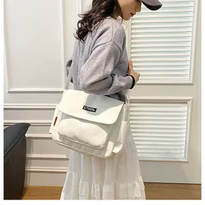 Detail of white canvas messenger bag with stylish black label and spacious side pocket