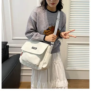 Detail of white canvas messenger bag featuring a Russian style patch and wide shoulder strap