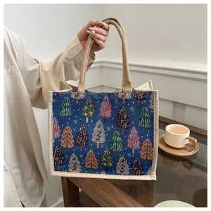 Detail of Christmas tree embroidery on blue jacquard linen tote bag with burlap handles