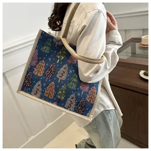 Detail of deep blue linen tote bag with colorful Christmas tree patterns and sturdy handles