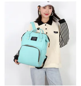 Detail view of the mint green diaper backpack featuring a fabric label on the front pocket