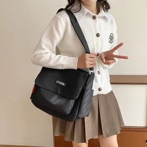 Minimalist black nylon messenger bag with white text patch and red side label detail