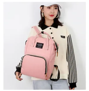 Pink multi-functional diaper backpack for moms featuring gold zippers and label detail
