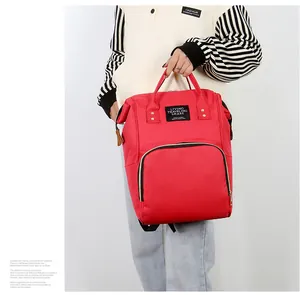 Close-up of red canvas mommy backpack with top handles and front pocket for travel