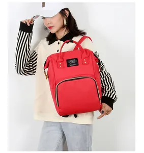 Close-up of red multifunctional mommy backpack featuring durable handles and front zip pocket