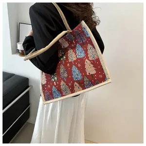 Close-up of red linen tote bag with colorful Christmas tree patterns and woven straps