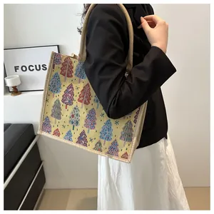 Detailed shot of a linen tote bag with colorful Christmas tree patterns on a model