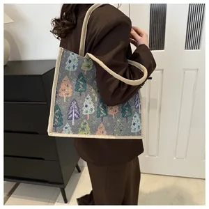 Detail of linen tote bag featuring festive Christmas tree patterns and woven rope handles