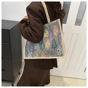 Linen tote bag with colorful Christmas tree patterns shown on a model's shoulder