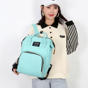 Large mint green mommy backpack diaper bag with multi-pockets shown on model