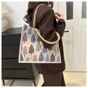 Close-up of woven linen tote bag with colorful Christmas tree jacquard and beige handle