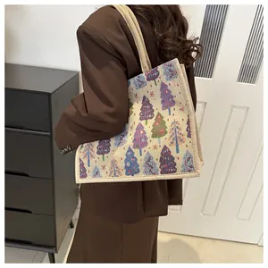 Lifestyle shot showing a linen tote bag with colorful Christmas tree embroidery details