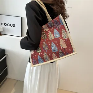Linen tote bag with red Christmas tree patterns and canvas handles worn by a model