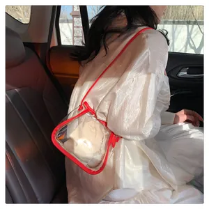 Dettaglio borsa a tracolla in PVC trasparente con bordo rosso e custodia interna