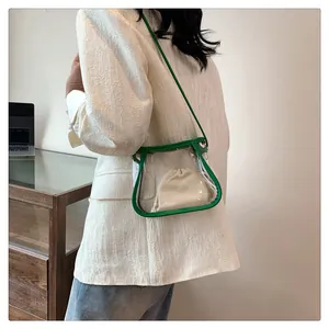 Borsa a tracolla trasparente in PVC con bordo verde e sacchetto beige indossata da modella