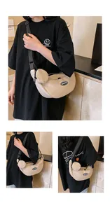 Detail view of beige crescent nylon crossbody bag with matching round coin purse charm