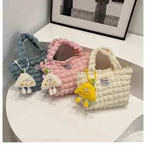 Detailed view of bubble texture handbags in blue, pink, and beige with plush pendants