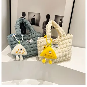 Detail of bubble textured handbag with cute plush monster charm and stylish white label