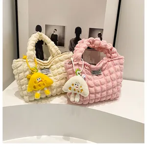 Close-up of quilted bubble texture fabric handbags in cream and pink with plush charms