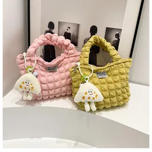 Macro detail of bubble textured fabric handbag with cute plush smiley keychain pendant