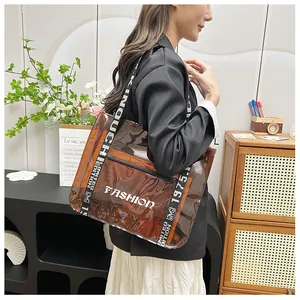 Detailed view of brown translucent PVC tote bag with white lettering and sporty strap