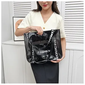 Detail of transparent PVC tote bag featuring black lettering and woven shoulder strap