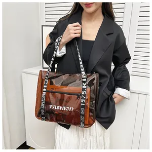Detail view of brown transparent PVC tote bag featuring black and white fashion strap