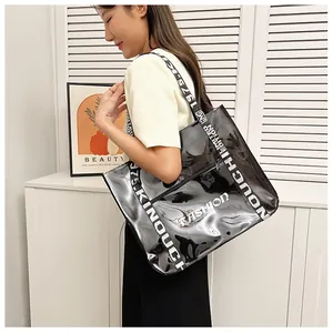 Detail of glossy black tote bag featuring bold white fashion slogans and a zipper pocket