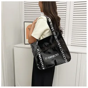 Macro view of black glossy tote bag featuring white FASHION print and lettered wide strap
