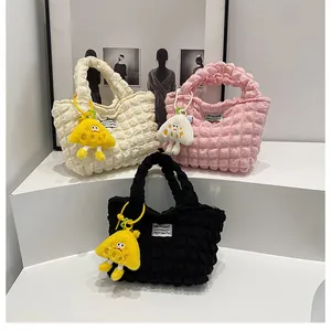 Primer plano de bolsos con textura de burbujas en beige, rosa y negro con colgantes
