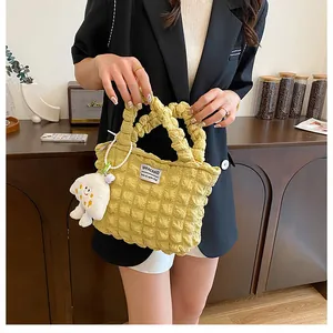 Detail of yellow bubble texture handbag with plush cloud charm and pearl chain accent