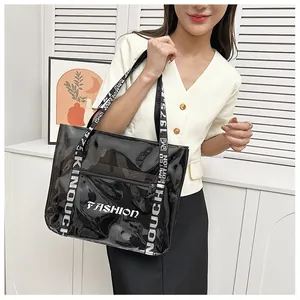 Detail of transparent PVC tote bag featuring black fashion lettering and wide shoulder strap