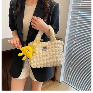 Detalle del bolso tote crema con textura de burbujas y colgante de peluche amarillo
