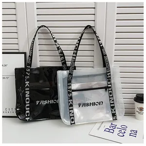 Detail of transparent PVC tote bag featuring white lettered wide shoulder straps and zip pockets