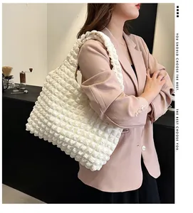Détail du sac à bandoulière blanc à texture popcorn porté par un mannequin en café