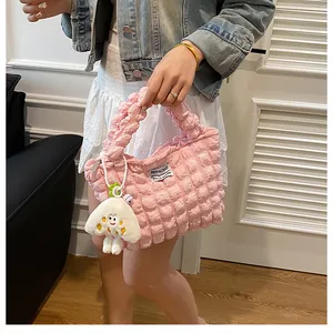 Primer plano detallado del bolso rosa con textura de burbuja y colgante de seta de peluche