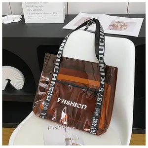 Close-up of brown transparent PVC tote with black 'LIMITED EDITION' straps and orange lining