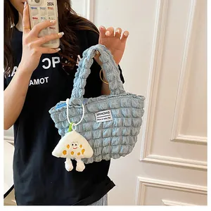 Detalle de bolso azul claro con textura de burbujas y colgante de peluche de monstruo