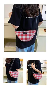 Detail of red and white checkered crescent crossbody bag with adjustable black strap