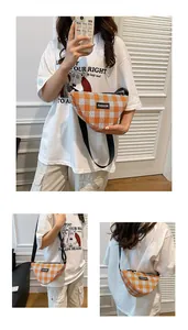 Detail view of orange and white plaid crossbody dumpling bag with adjustable black strap